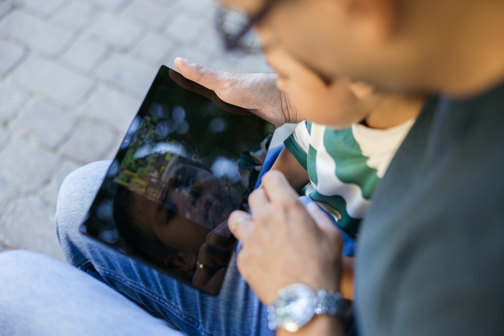 Un bimbo con suo papà osservano lo schermo di un table