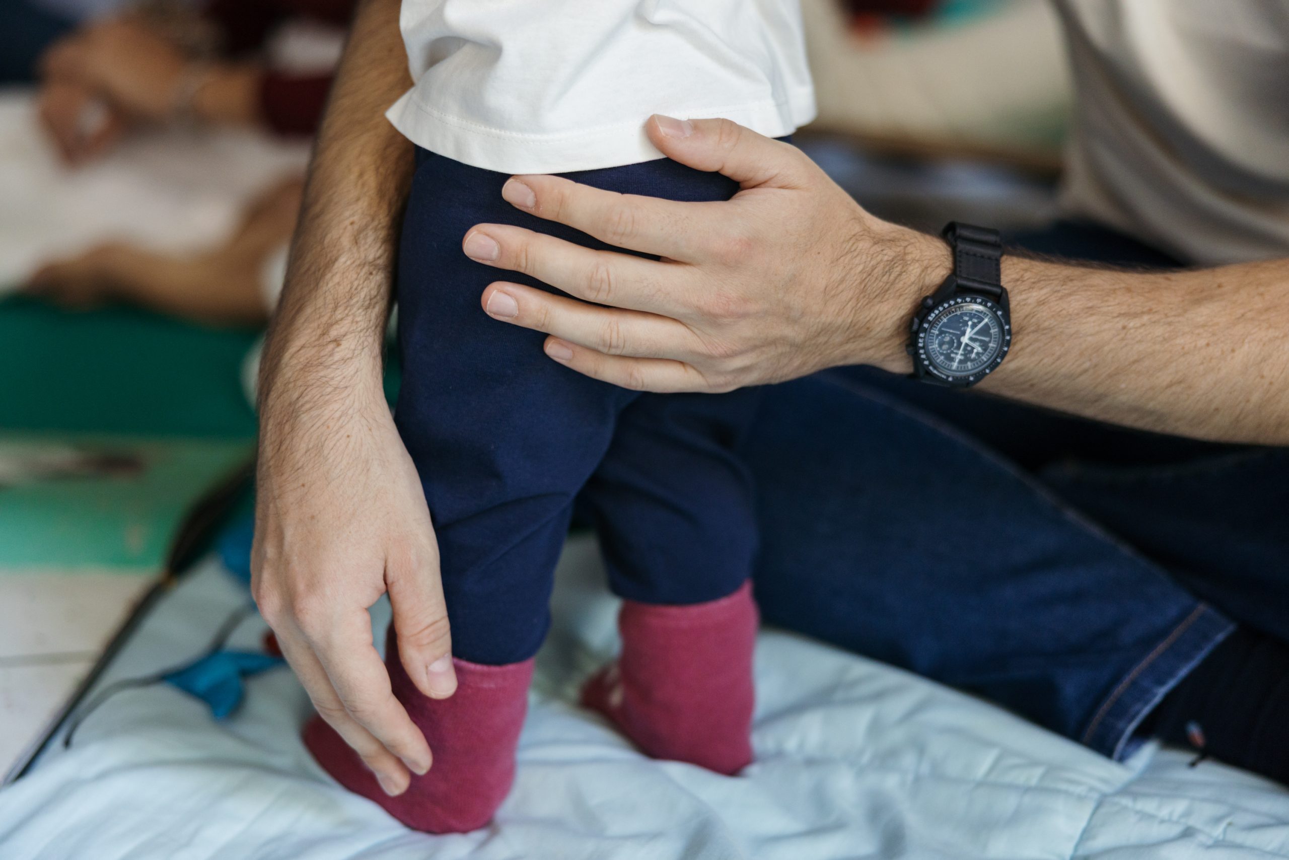 Un padre sorregge il figlio molto piccolo alle prese con i primi passi