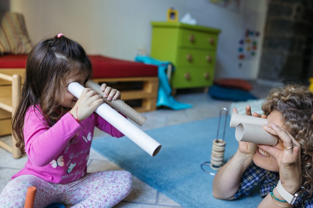 Una bimba e sua mamma giocano usando dei rotoli come cannocchiali